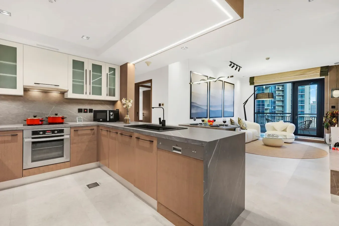 Una cocina moderna se abre a una sala de estar con ventanales y asientos.