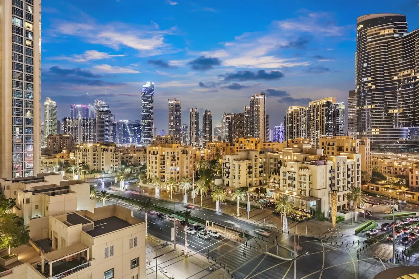 El horizonte urbano se alza sobre edificios de apartamentos y calles iluminadas al anochecer.