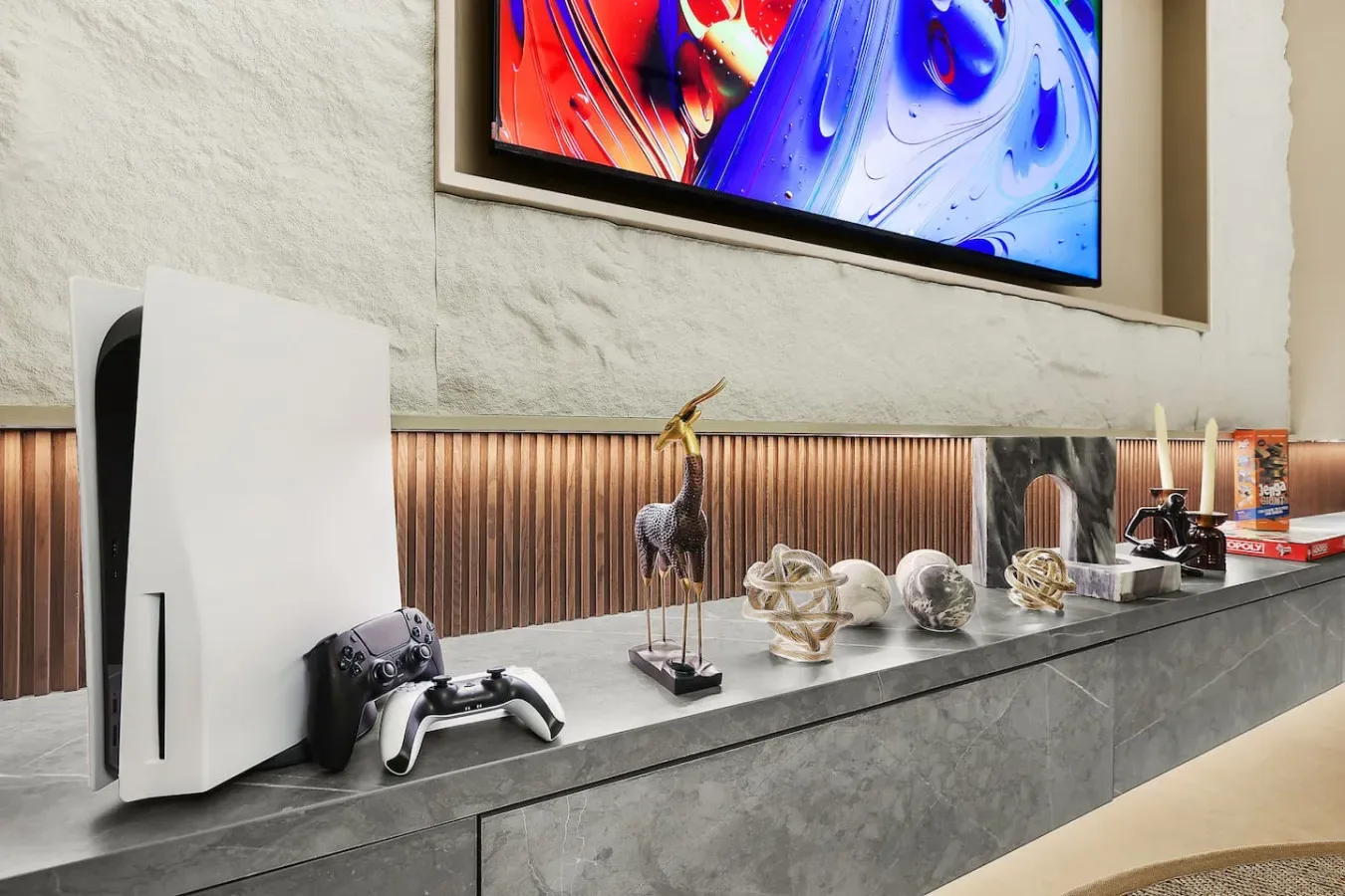 Un mueble multimedia exhibe una consola de videojuegos, figuras decorativas y un televisor.