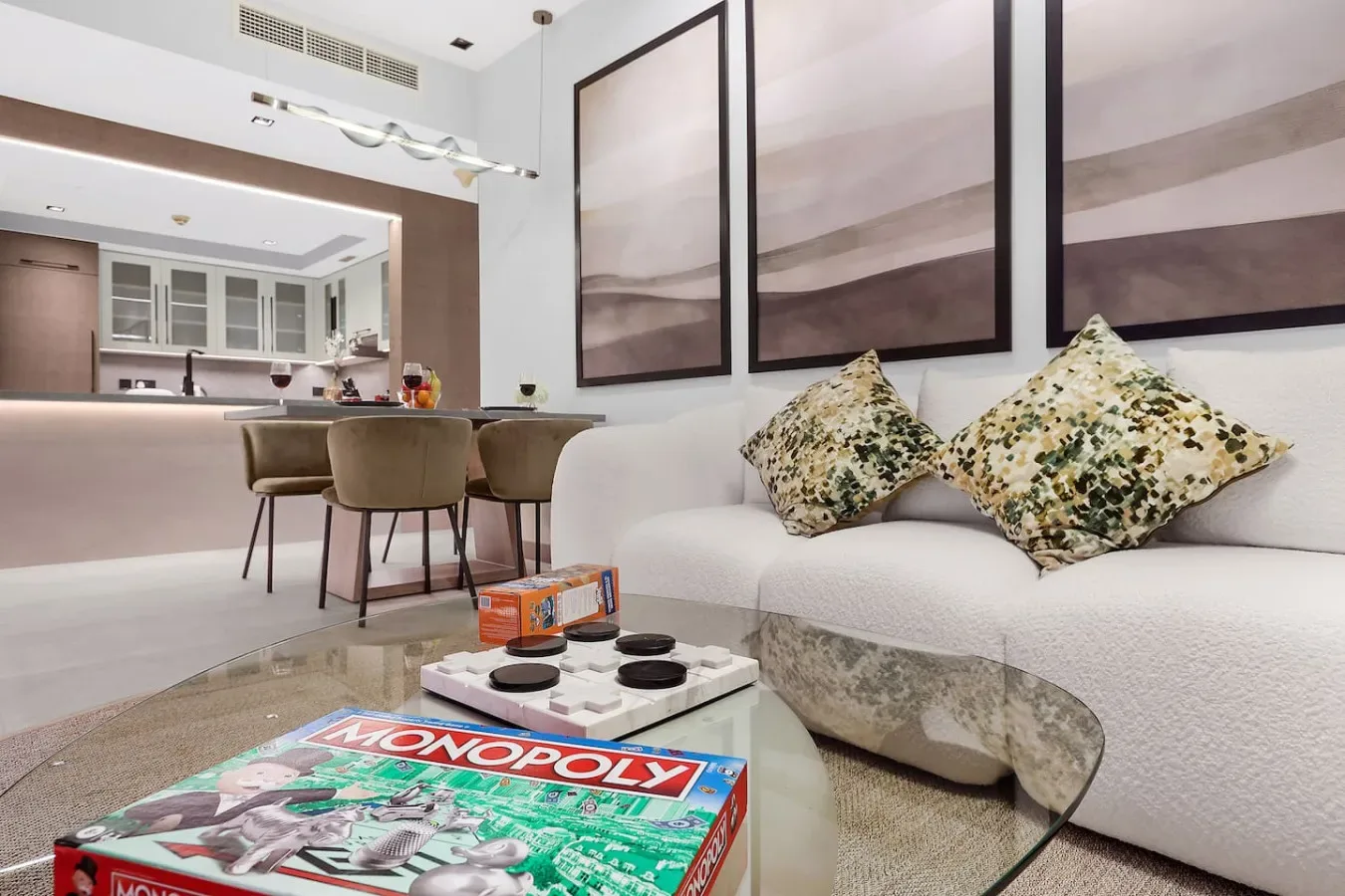 Una sala de estar moderna con sofá, mesa de centro de vidrio y cocina abierta.