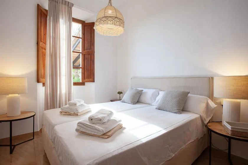 A bright bedroom with a neatly made bed beneath an open window.