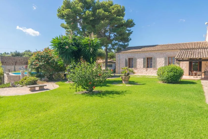 A landscaped garden with a broad lawn, trees, and a stone house.