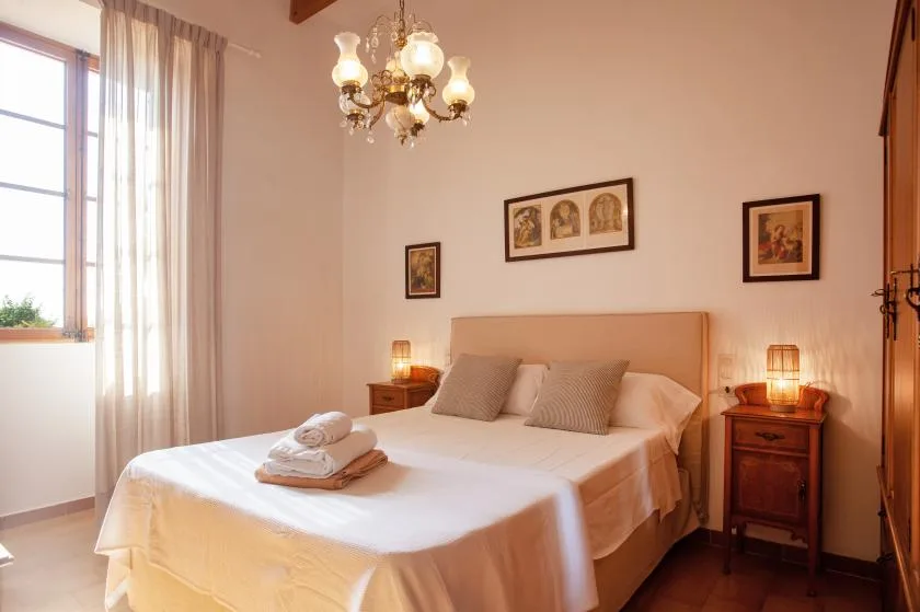 A bedroom with a neatly made bed, bedside tables, and framed artwork.
