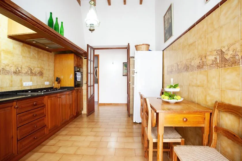 A tiled kitchen and dining area with wooden cabinets, a table, and chairs.