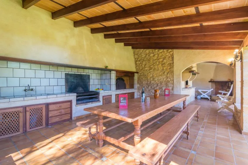 A rustic dining area with a long wooden table beneath exposed ceiling beams.