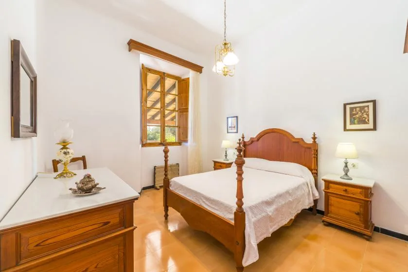 A bedroom with a wooden bed and a window.