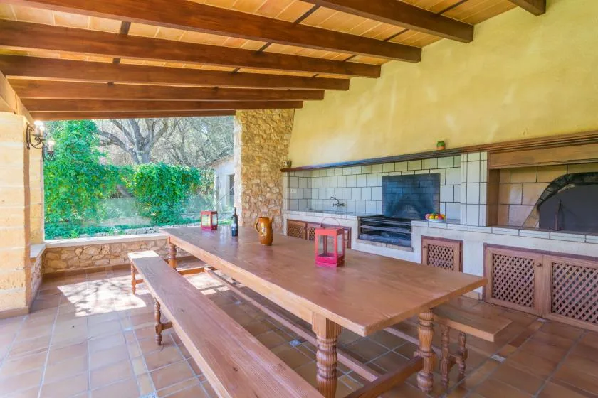 A rustic dining area with a long wooden table and a fireplace along the wall.