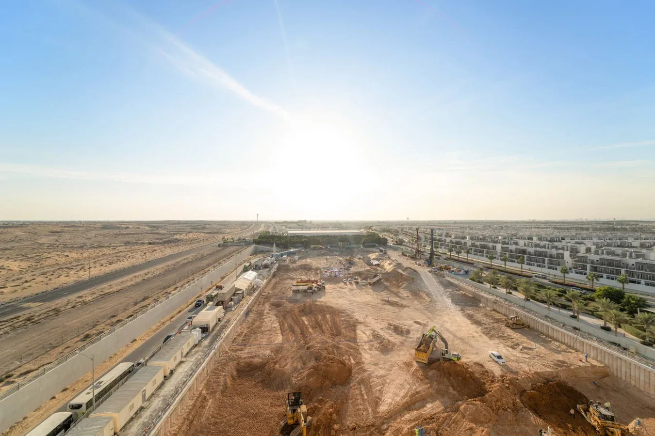 An aerial view shows a large construction site with earthmoving equipment.