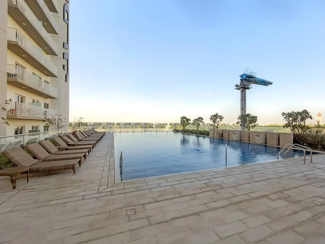 An outdoor swimming pool beside a building, with lounge seating along the deck.