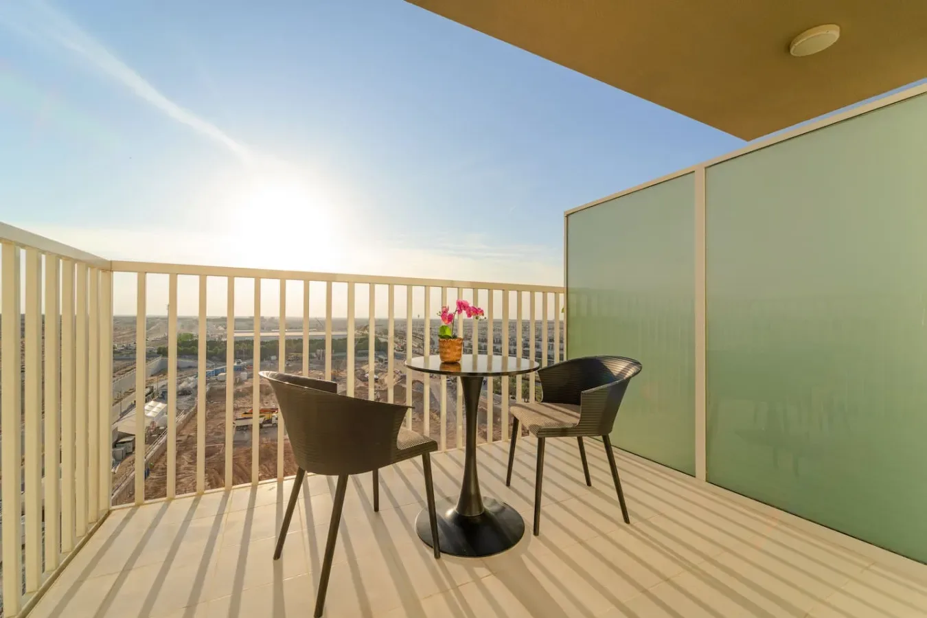 A balcony seating area has a small table with flowers and an open view.