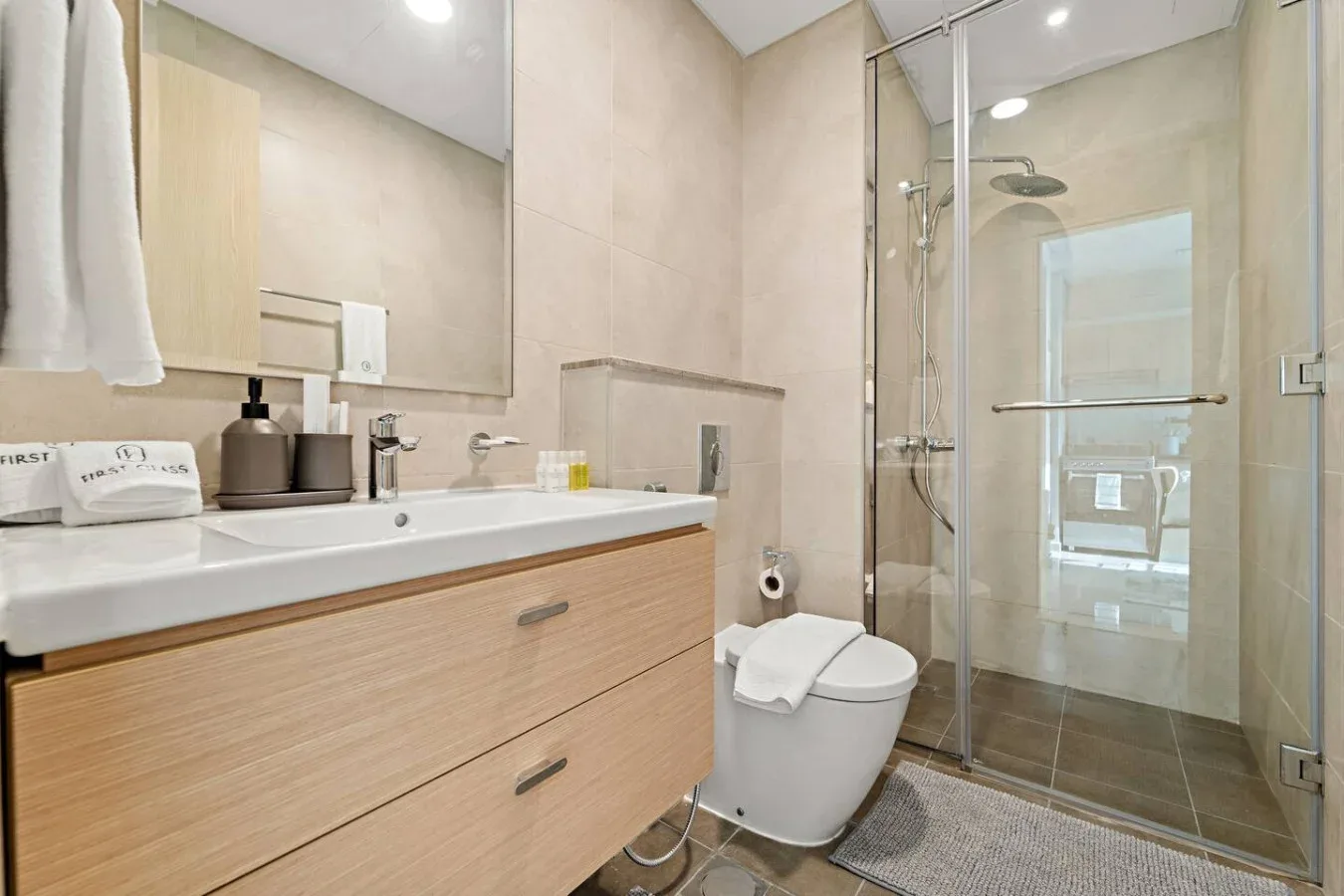 A modern bathroom with a vanity, toilet, and glass shower.