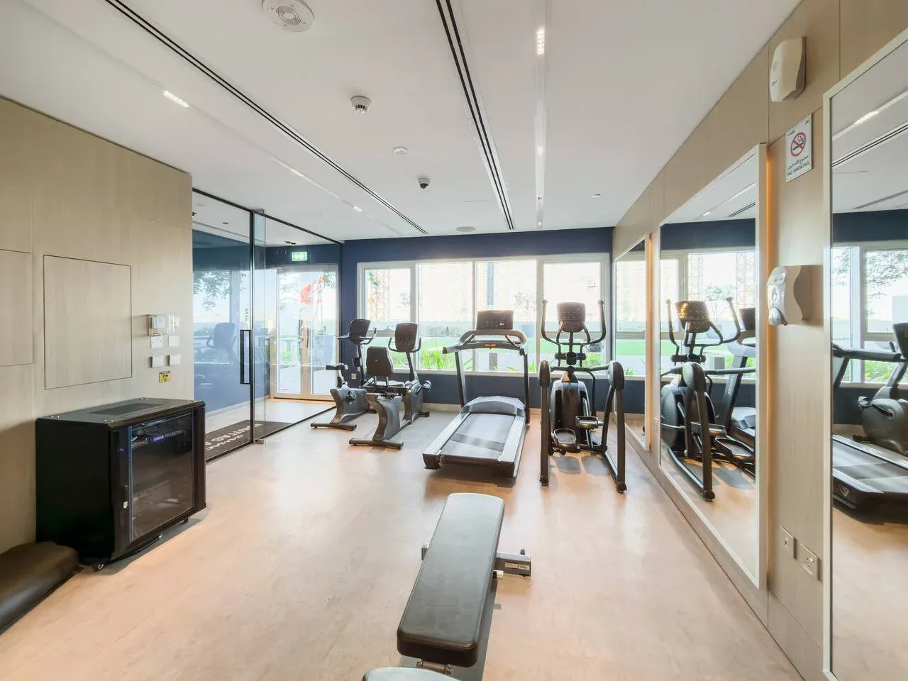 A fitness room with exercise equipment and mirrored walls.