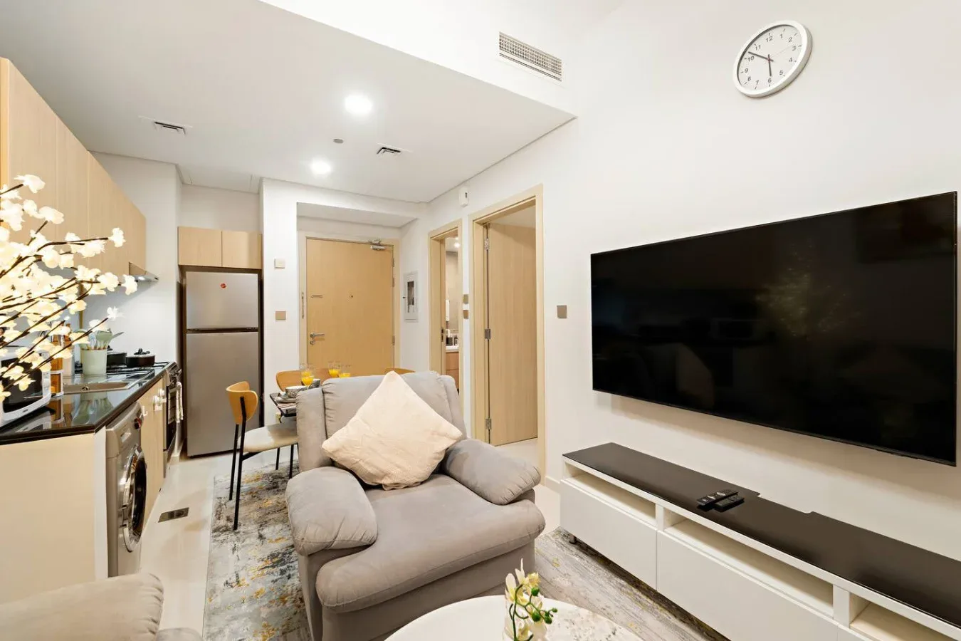 A bright living area with a sofa and a wall-mounted television.