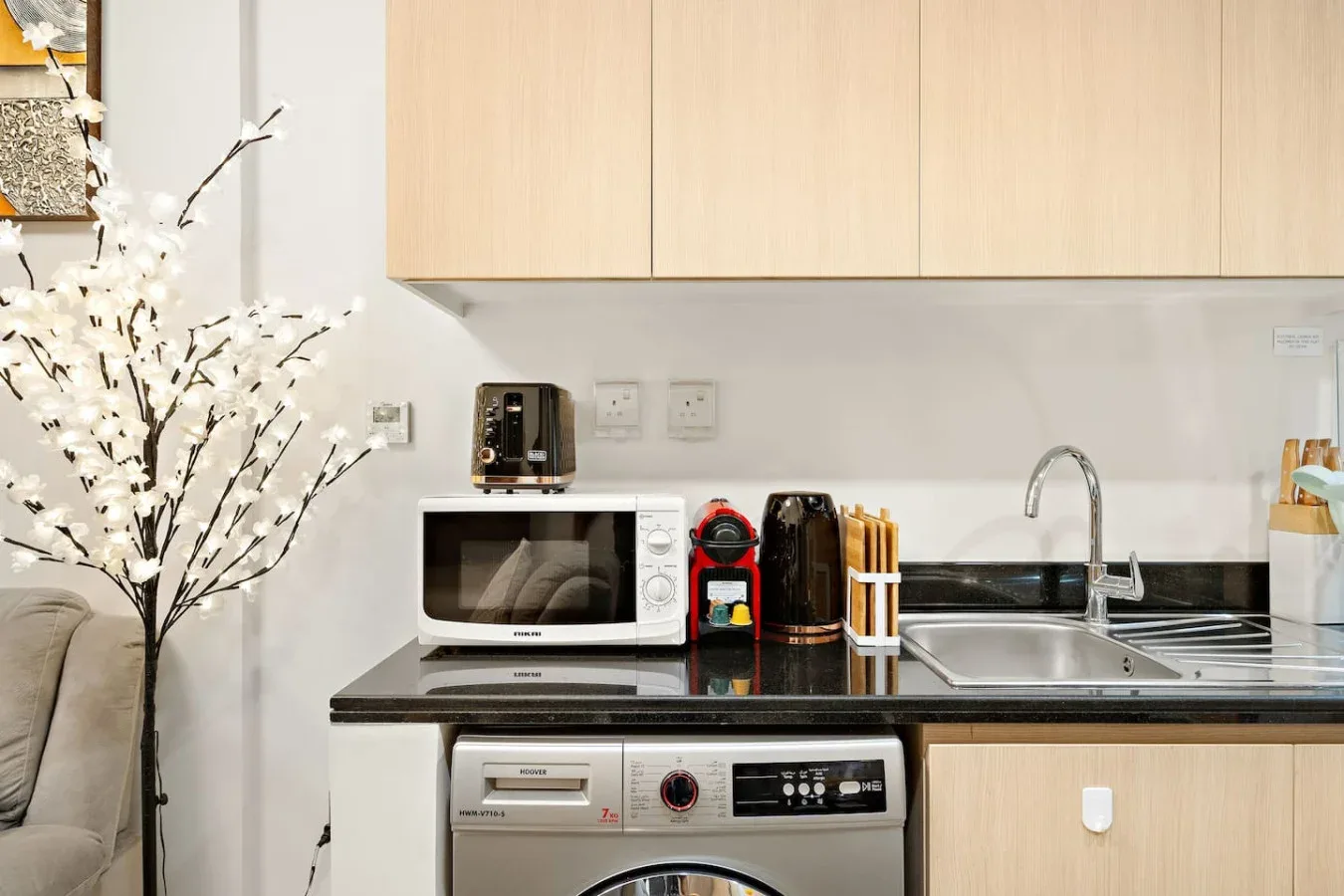 A compact kitchen area has light cabinets, a sink, and countertop appliances.