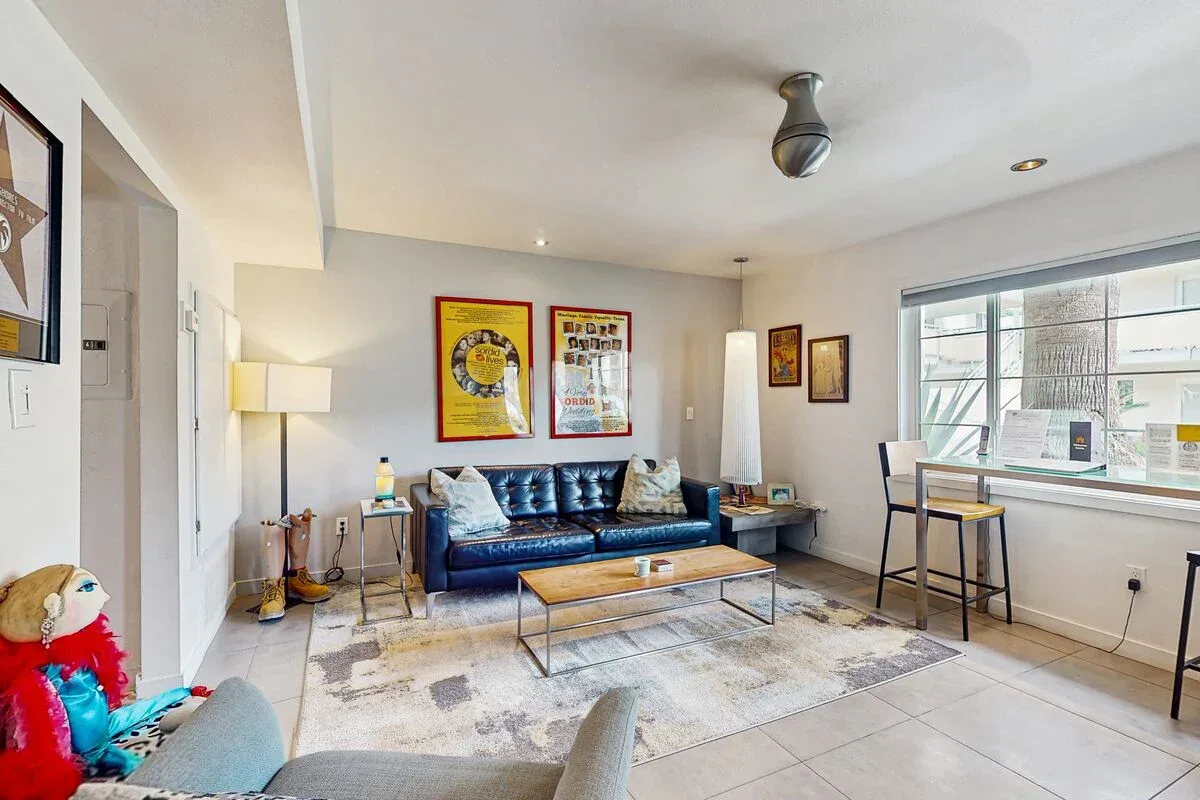 A bright living room with a blue sofa, coffee table, and large window.