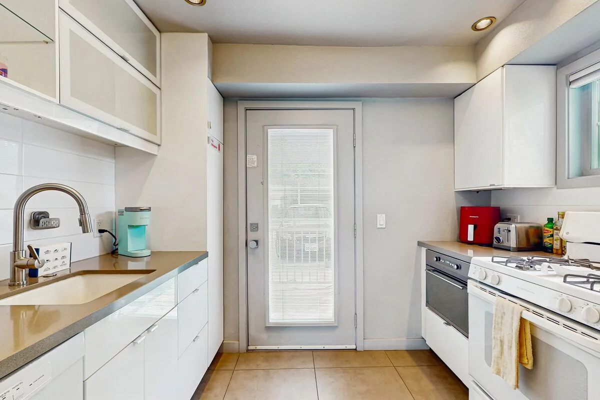 A bright kitchen with counters and appliances on either side of a glass-paneled door.