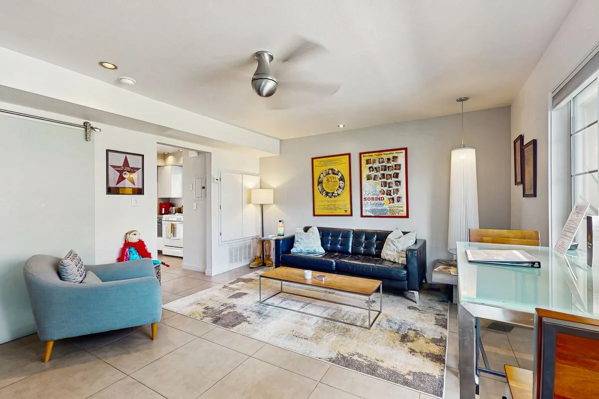 A bright living room with a sofa, armchair, and glass coffee table.