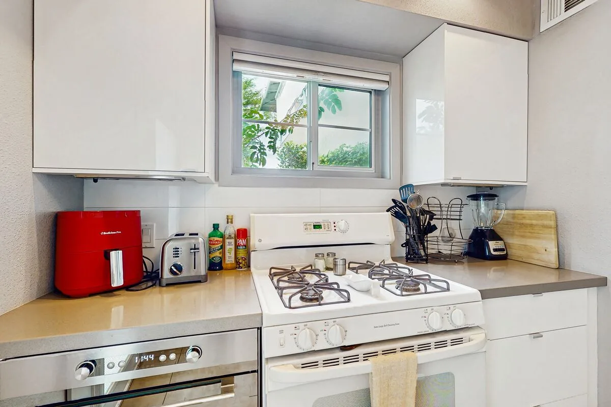 A bright kitchen with a white stove beneath a window.