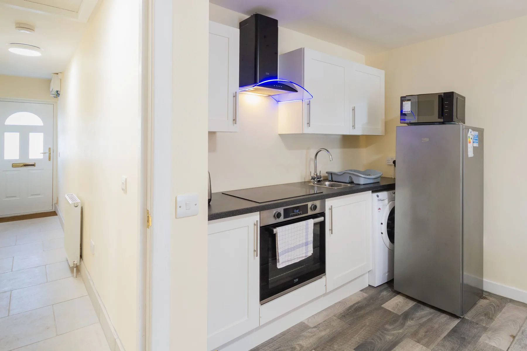 A bright kitchen with white cabinets, a counter, and stainless steel appliances.
