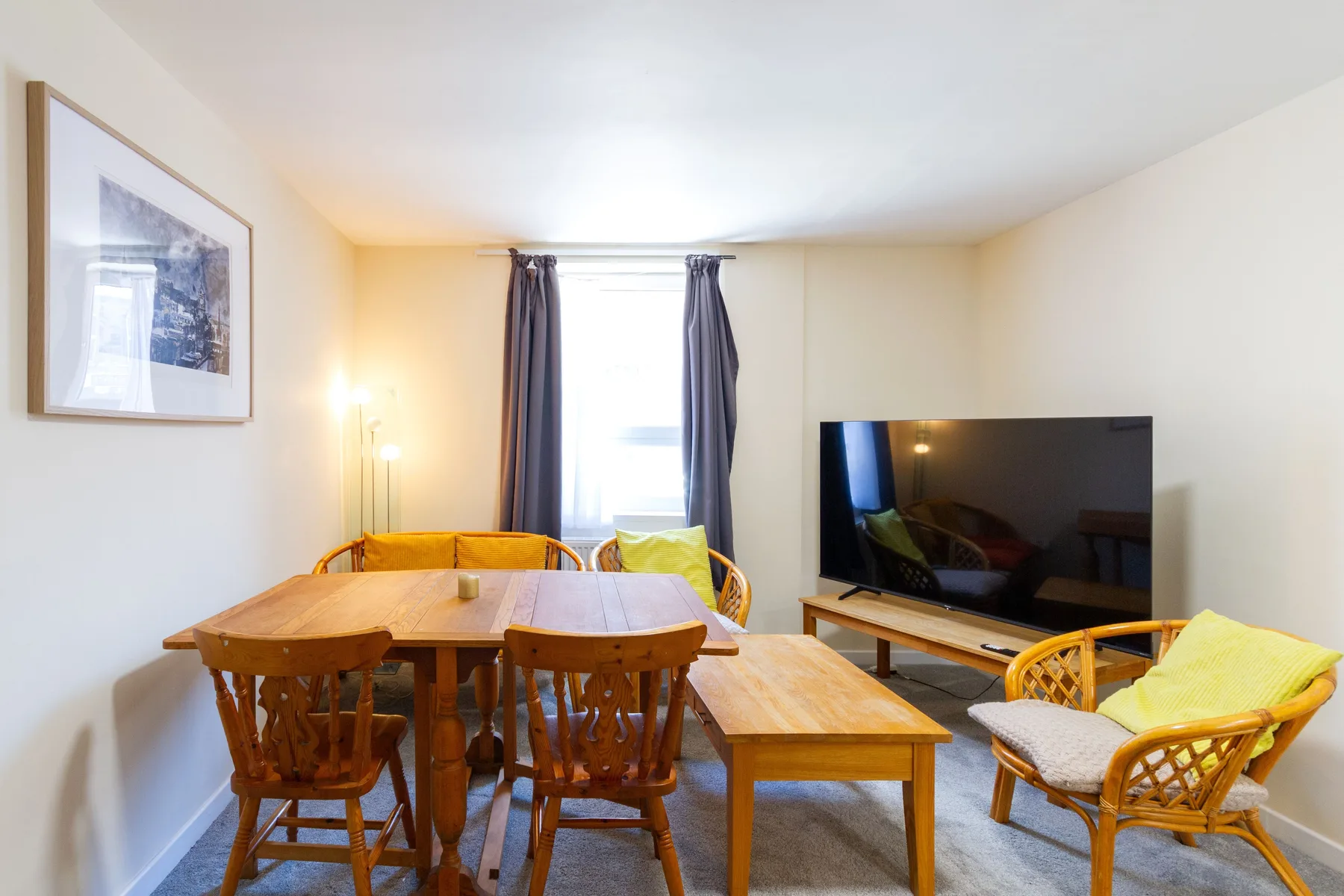 A living and dining area with a wooden table, seating, and television.