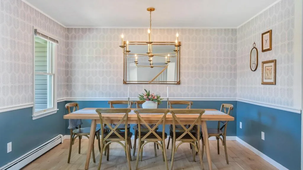 A dining room with a long table, chairs, and a hanging light.