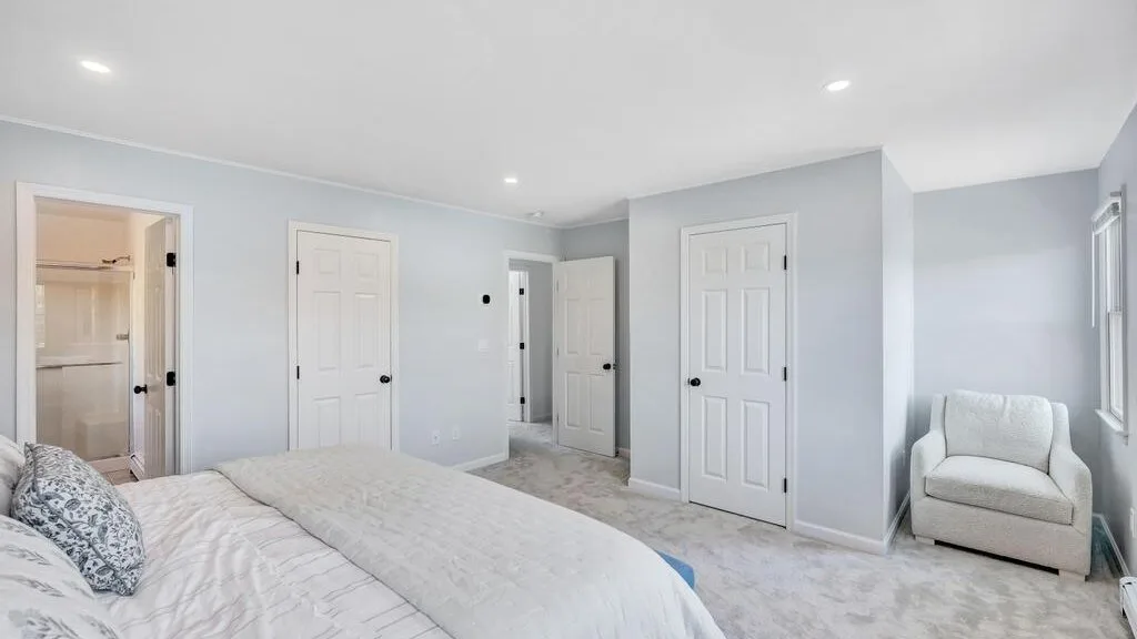 A bright bedroom with a bed and an armchair beside the window.