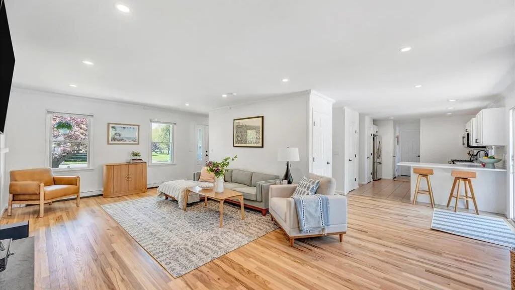 A bright living room opens onto a kitchen, with seating arranged around a coffee table.