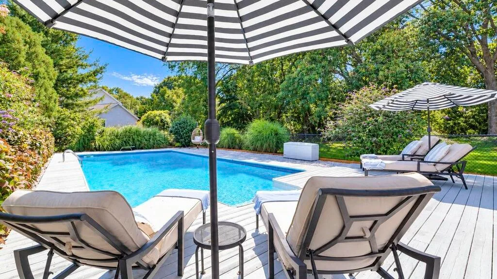 A poolside patio with lounge seating beneath striped umbrellas.