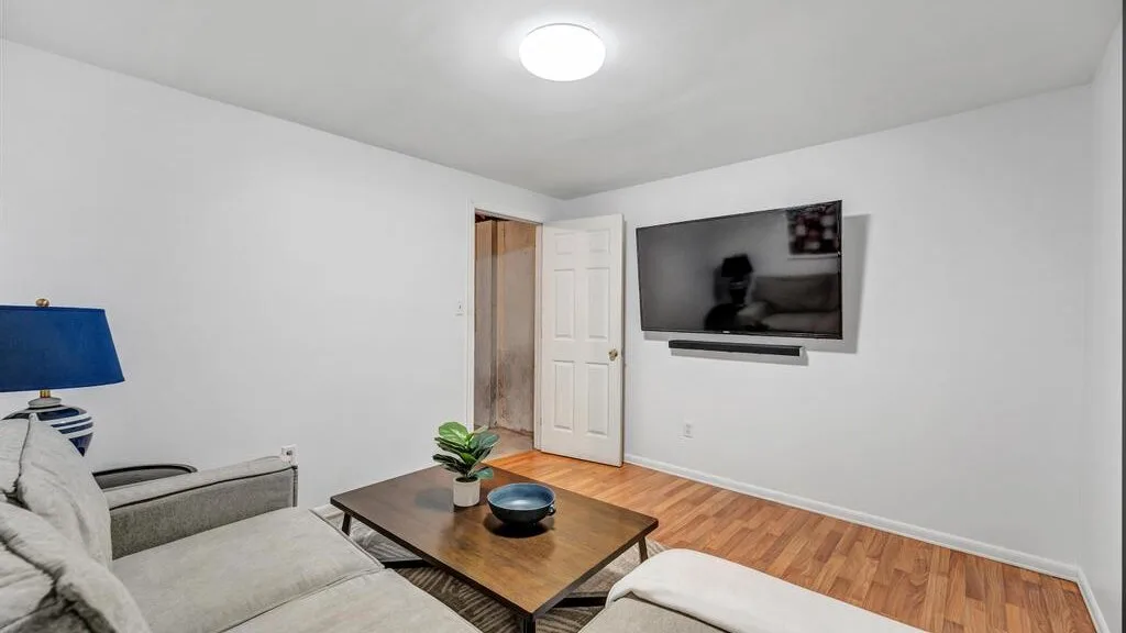 A living room with seating, a coffee table, and a wall-mounted television.
