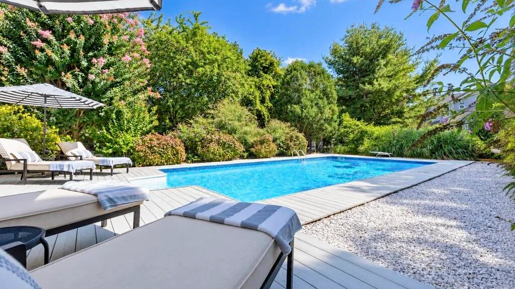 An outdoor swimming pool beside lounge seating and a gravel path.