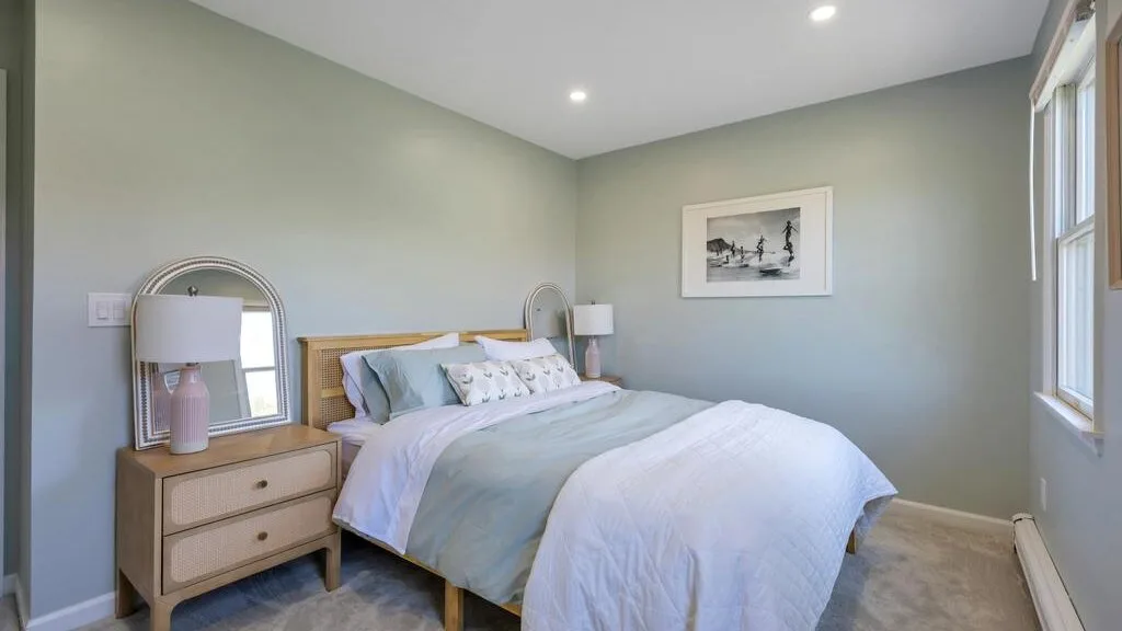 A bedroom with a bed dressed in pale blue and white bedding.