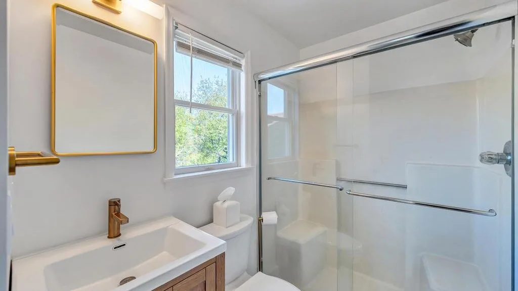 A bright bathroom with a sink, toilet, and glass shower.
