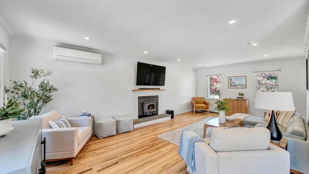 A bright living room with seating, a fireplace, and a television.