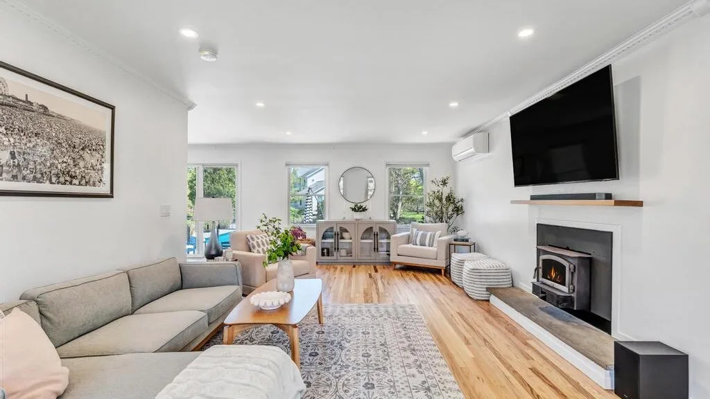 A bright living room with seating, a patterned rug, and a fireplace.