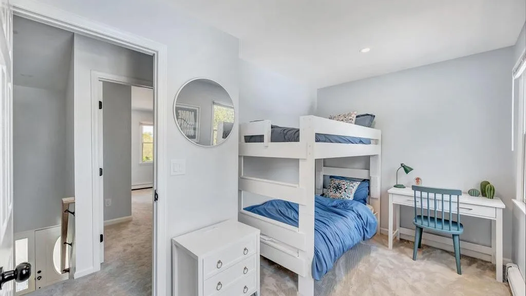 A bright bedroom with bunk beds, a desk, and a dresser.