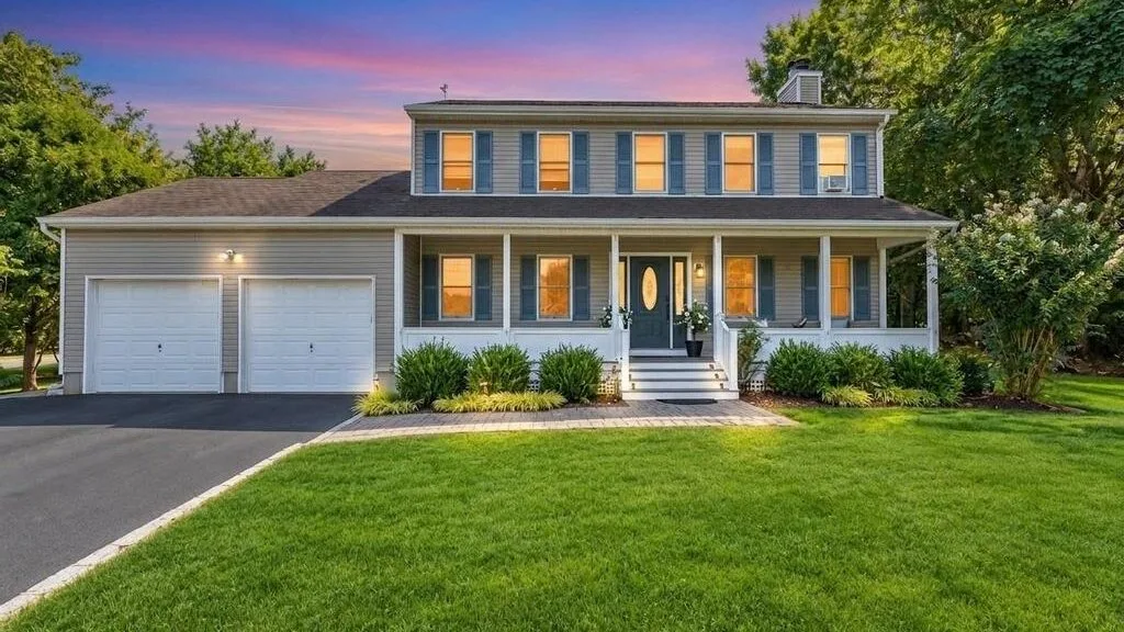 A two-story house with an attached garage stands behind a green lawn.