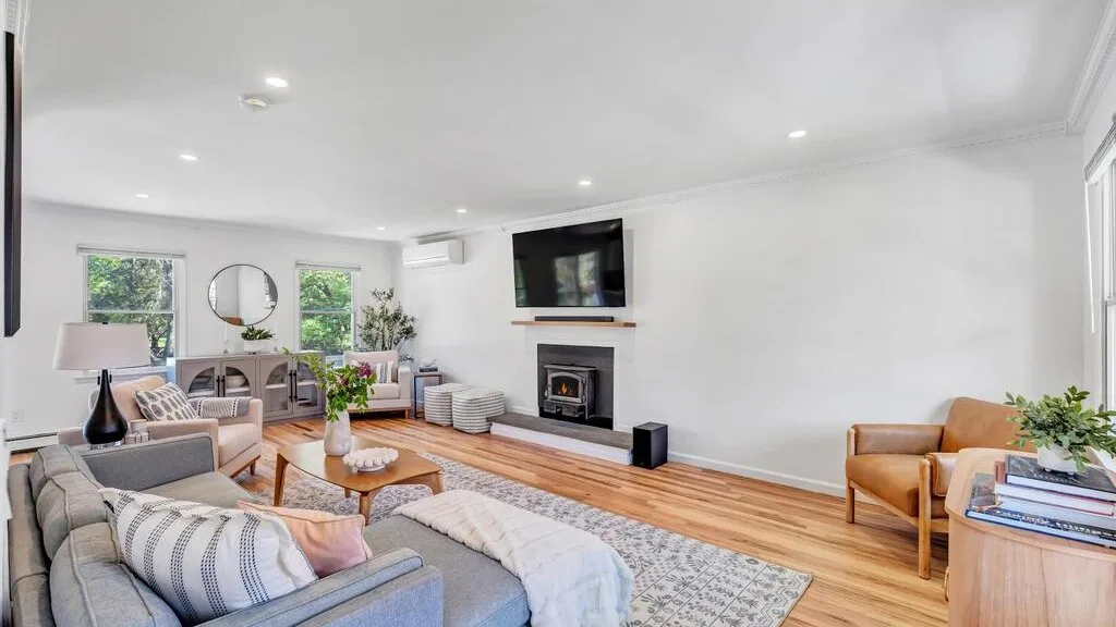 A bright living room with seating, a fireplace, and a television.