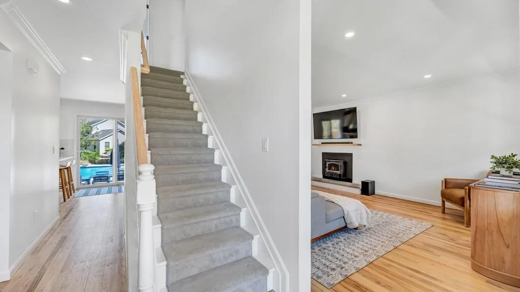 A bright interior hallway with a staircase beside a bedroom.