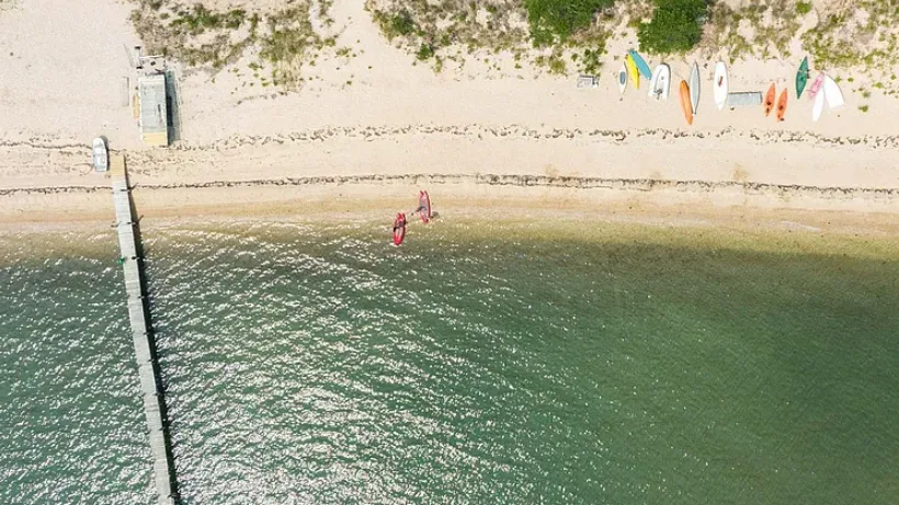 An aerial view of a sandy beach with colorful boards along the shore.