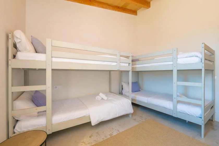 Un dormitorio con dos literas y ropa de cama blanca.