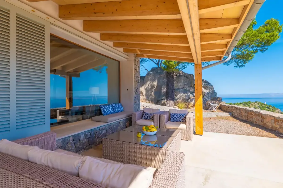 Un patio cubierto tiene asientos de mimbre junto a un gran ventanal.