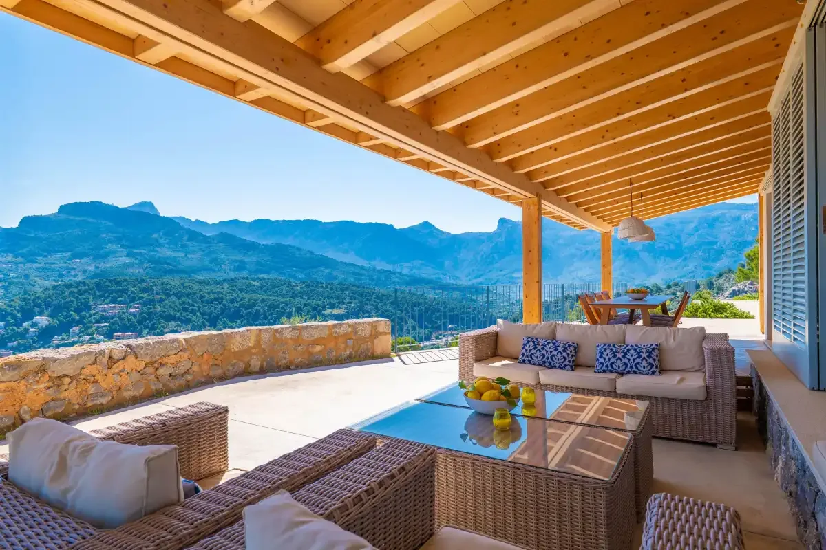 Una terraza exterior cubierta con asientos tiene vistas a un paisaje montañoso.