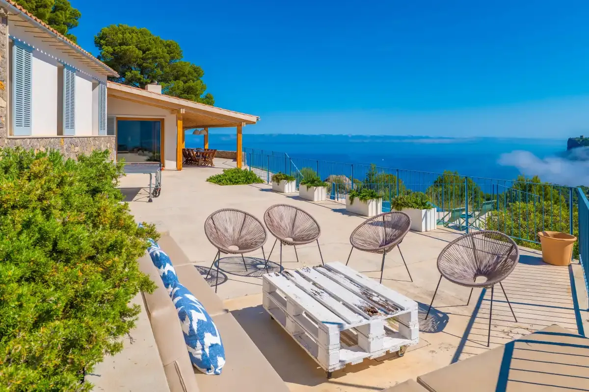 Un patio junto al mar tiene asientos al aire libre y vistas al agua azul.
