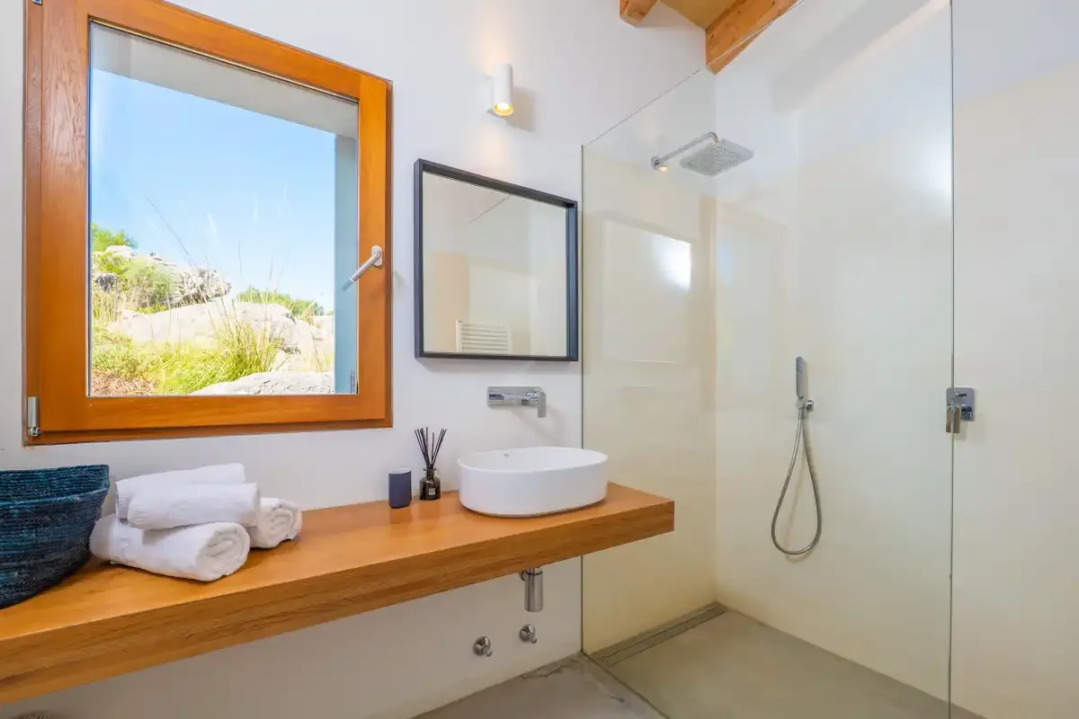 Un baño con una encimera de madera, lavabo y ducha de cristal.