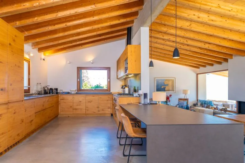 Una cocina con gabinetes de madera y una gran isla bajo vigas expuestas.