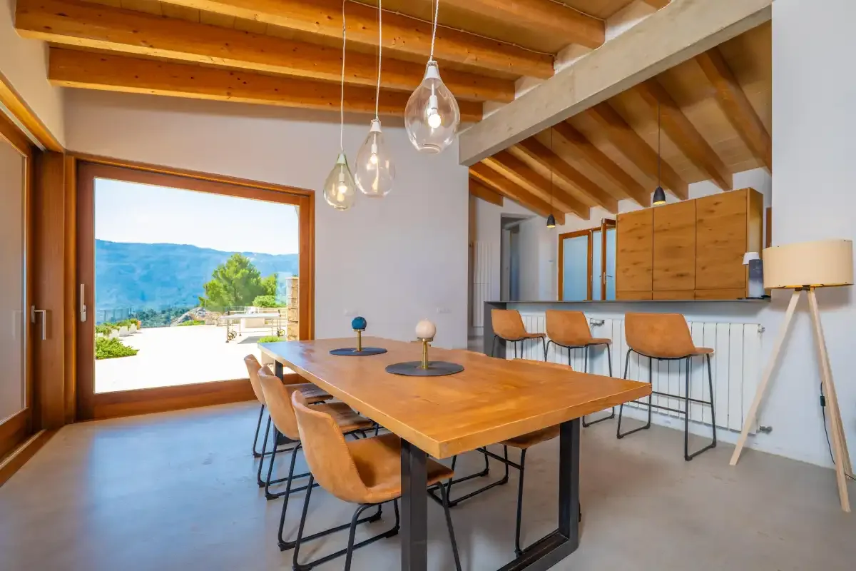 Comedor con una mesa de madera y asientos de barra junto a la cocina.