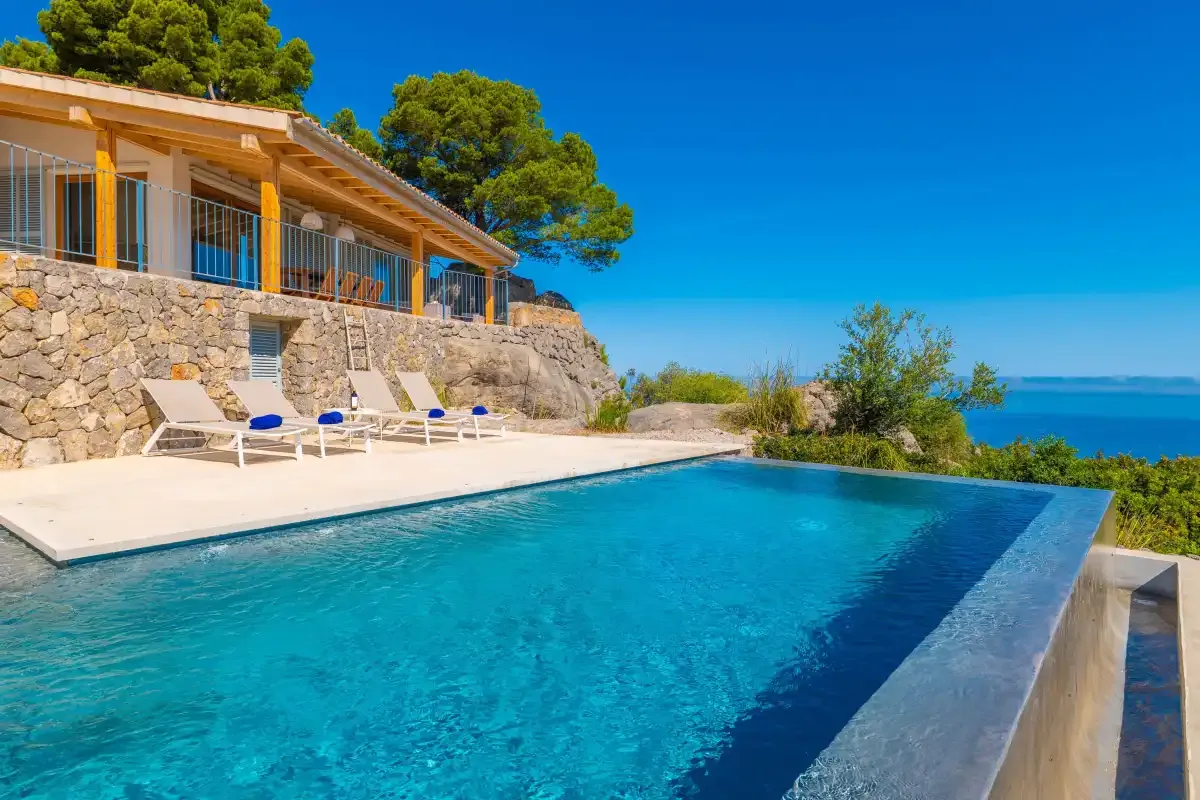 Una piscina junto a una terraza de piedra tiene vistas al mar.