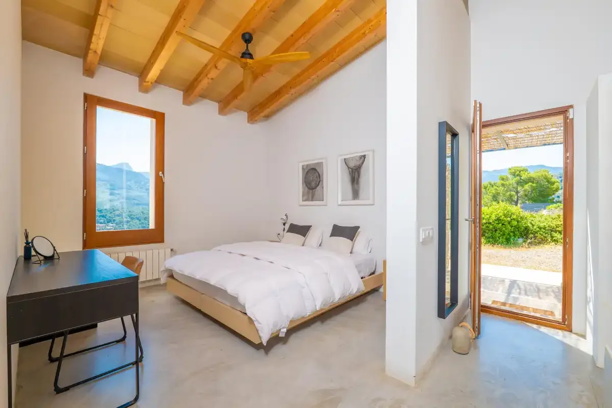 Un dormitorio luminoso con una cama doble y una ventana con vistas a la vegetación.