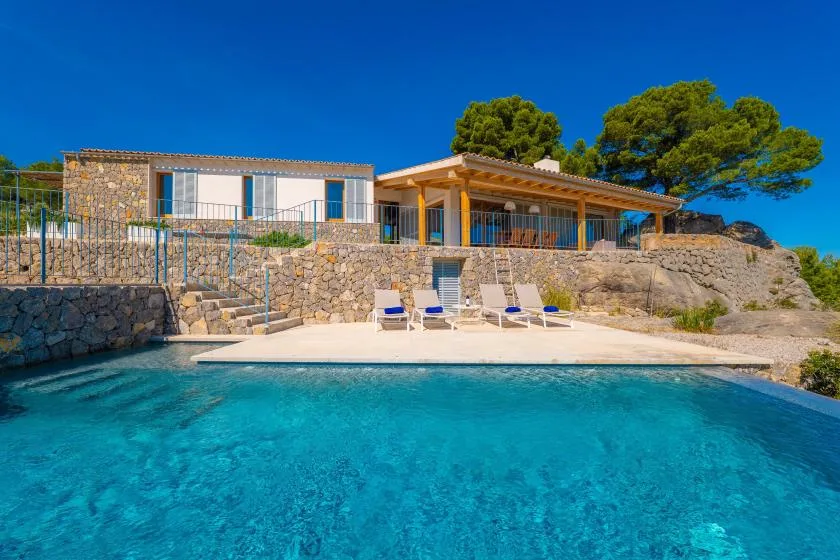 Una piscina y una terraza con asientos frente a una casa.