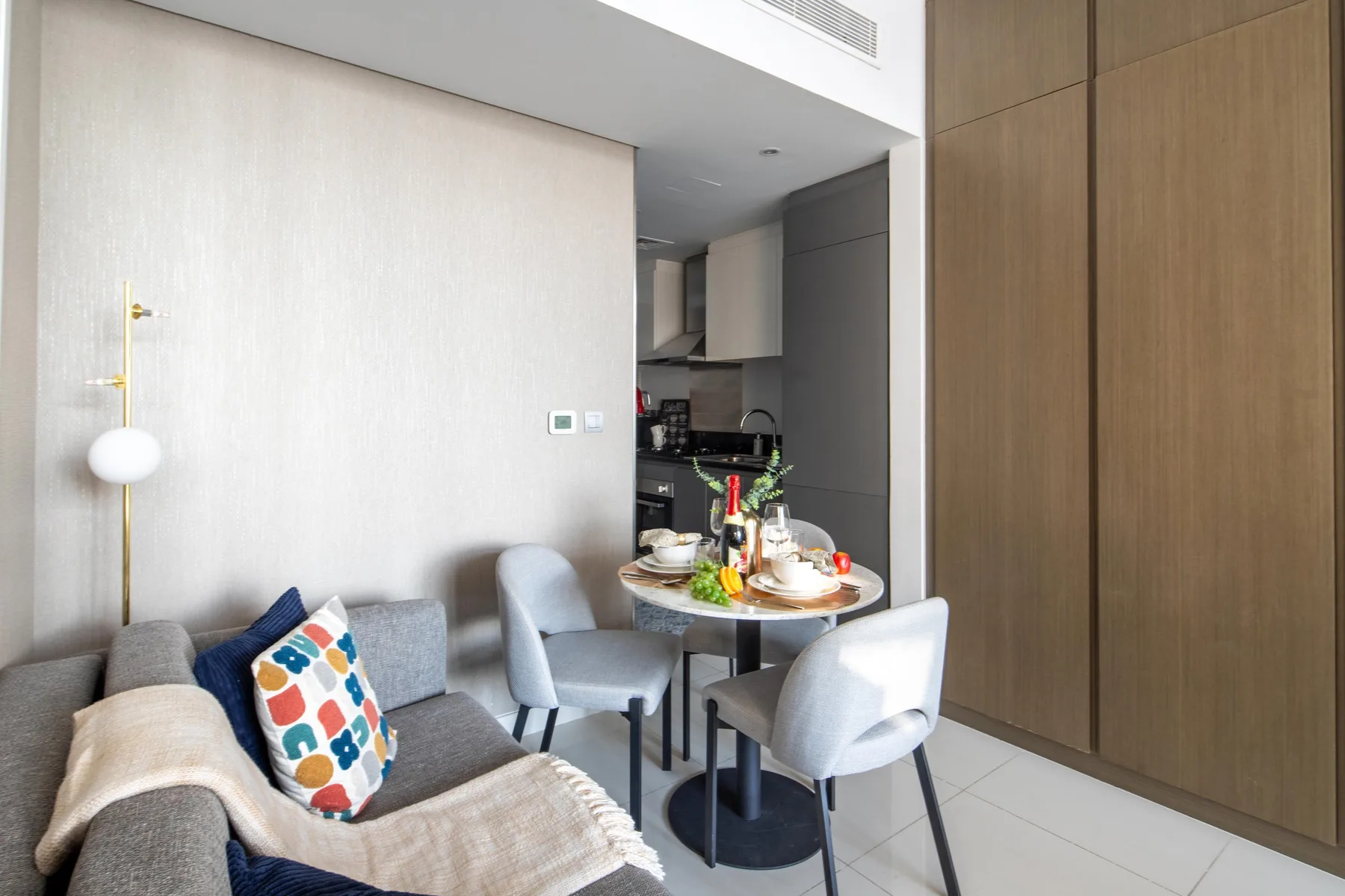 A dining area with a table and chairs sits beside a small kitchen.
